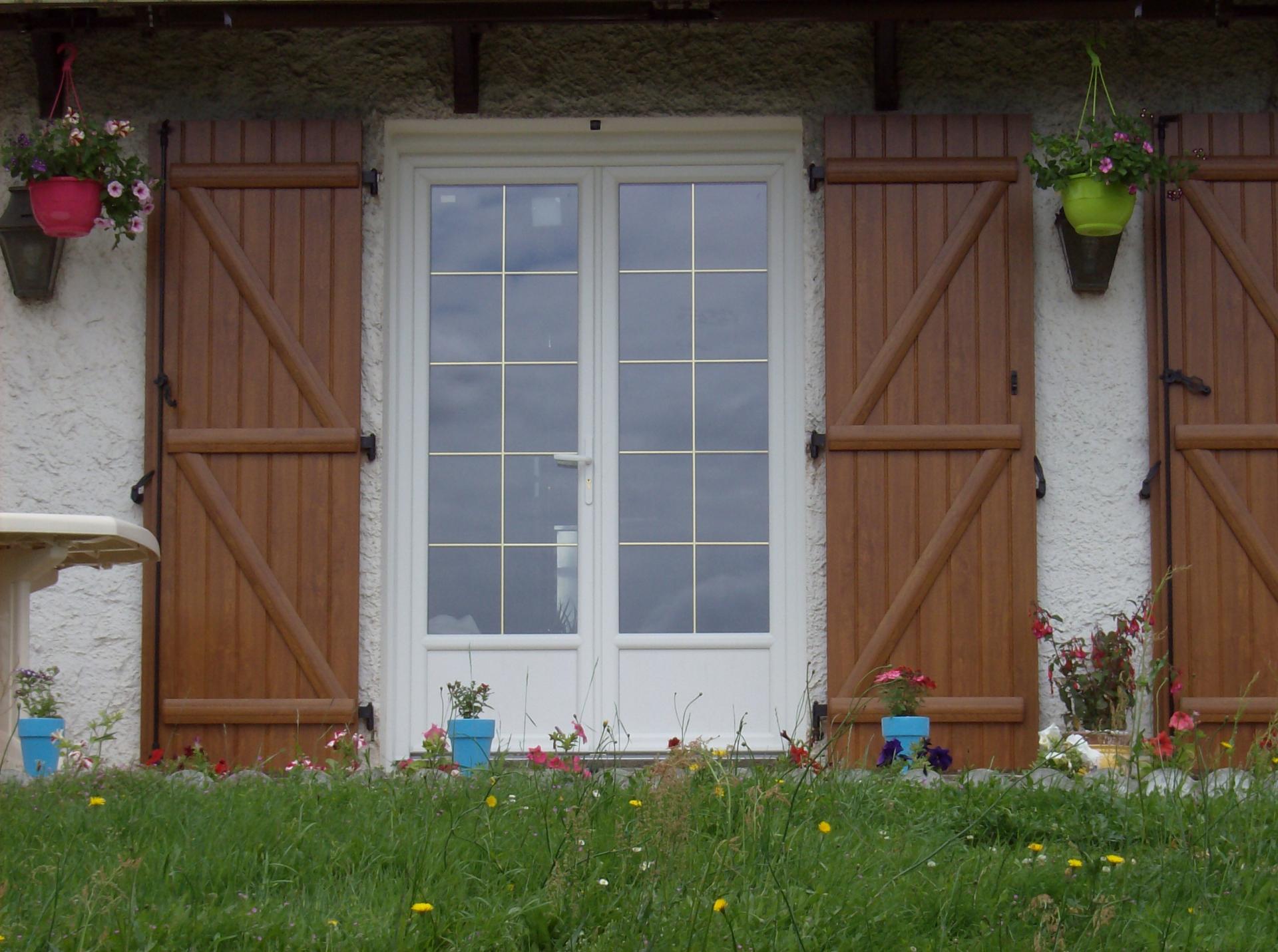 Porte-fenêtre avec petits bois laiton intégrés et volets PVC coloris chêne doré
